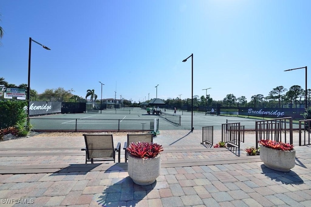 view of community with a tennis court and fence