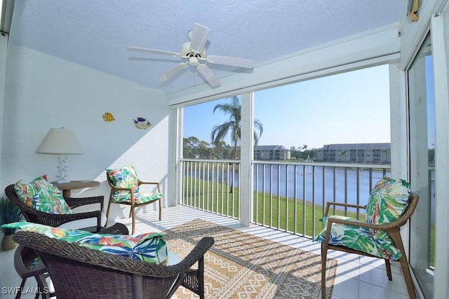 sunroom featuring a water view and a ceiling fan