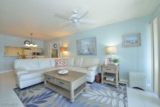 living room with ceiling fan with notable chandelier, baseboards, and light tile patterned floors