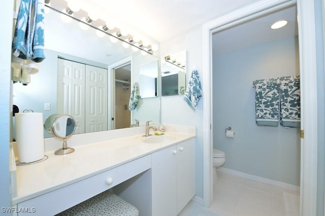 bathroom with tile patterned flooring, baseboards, vanity, and toilet