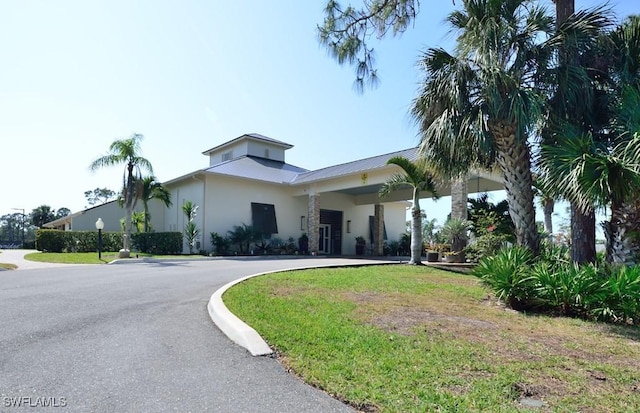 view of front of house with driveway, a front lawn, and stucco siding