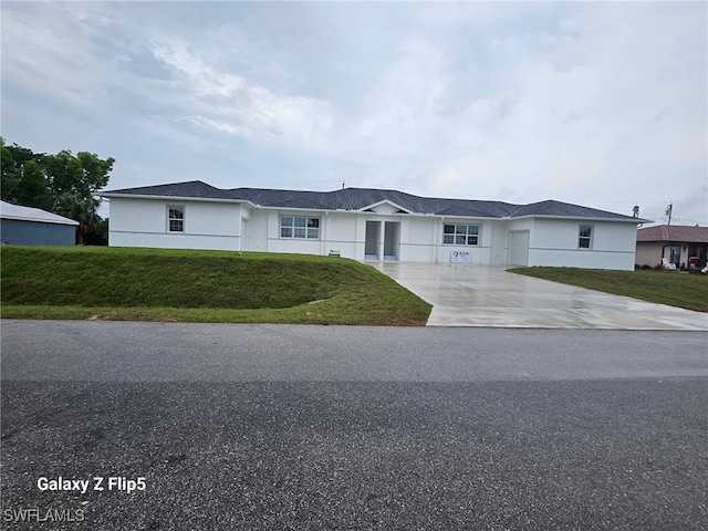 single story home with stucco siding, concrete driveway, and a front yard