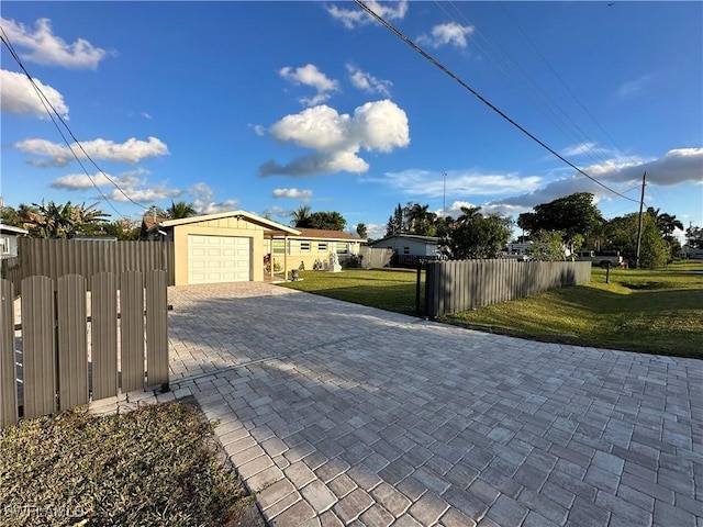 exterior space with a fenced front yard, decorative driveway, a lawn, and a garage