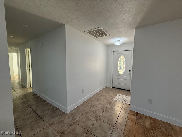 tiled entryway featuring baseboards, visible vents, and a textured ceiling