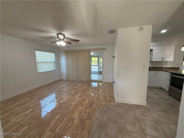 interior space featuring visible vents, a ceiling fan, and baseboards