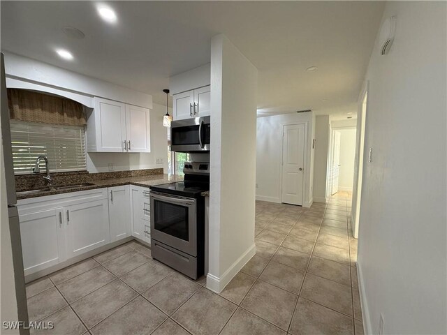 kitchen with light tile patterned flooring, appliances with stainless steel finishes, white cabinetry, and a sink