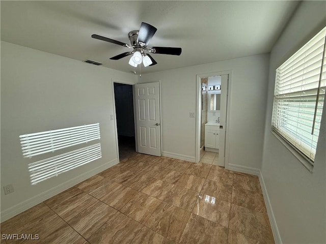 unfurnished bedroom featuring visible vents, baseboards, a ceiling fan, and ensuite bathroom