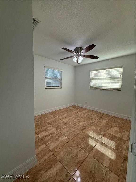 unfurnished room featuring a textured ceiling, baseboards, and a ceiling fan