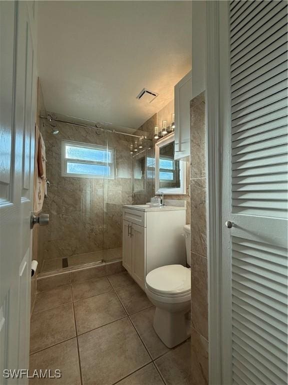 bathroom with toilet, a stall shower, tile walls, tile patterned flooring, and vanity