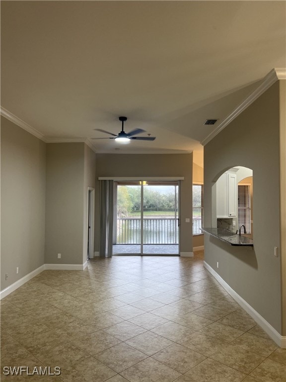 empty room with crown molding, baseboards, a water view, arched walkways, and a ceiling fan