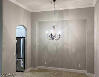 unfurnished dining area featuring an inviting chandelier, crown molding, and baseboards