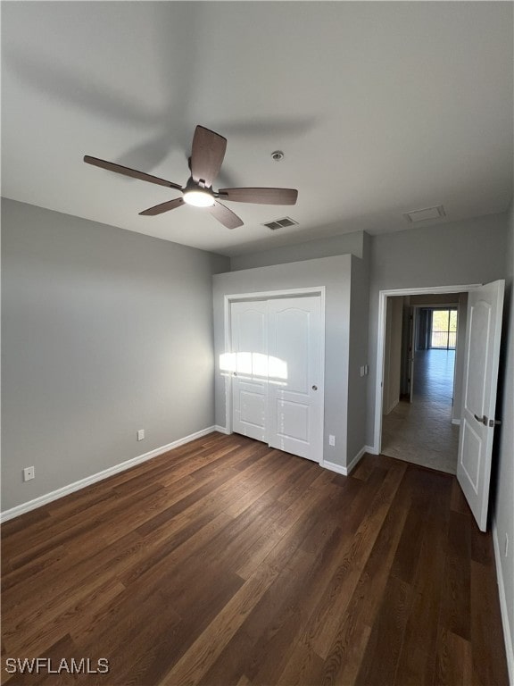 unfurnished bedroom featuring visible vents, baseboards, dark wood-style floors, and a ceiling fan