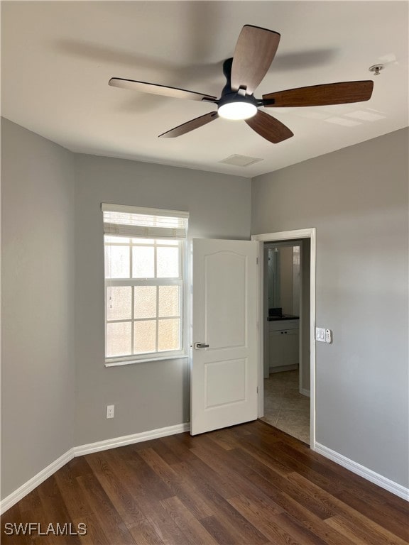 unfurnished bedroom featuring visible vents, ceiling fan, baseboards, and dark wood-style flooring