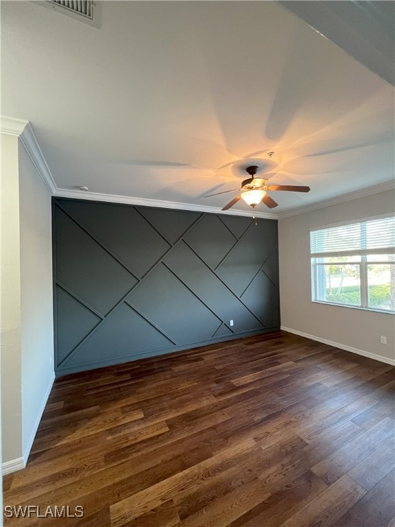 empty room with baseboards, visible vents, ceiling fan, dark wood-type flooring, and crown molding