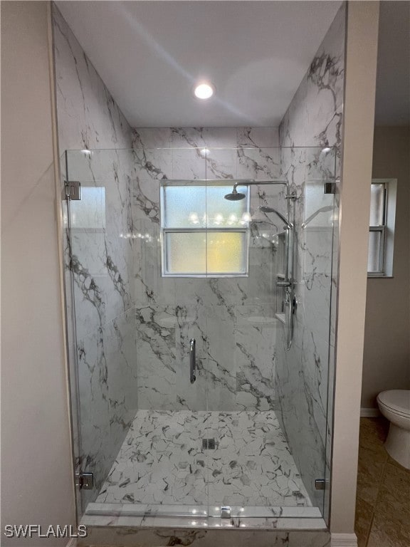 bathroom with a marble finish shower, toilet, and baseboards