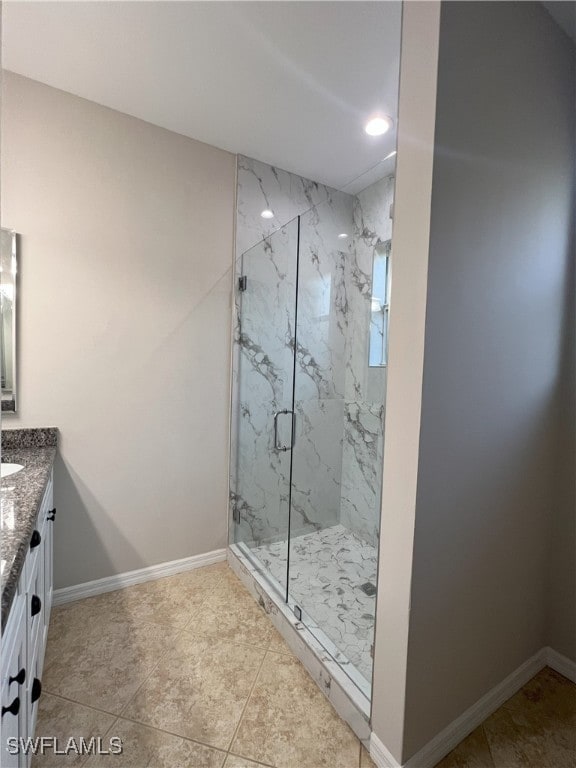 full bathroom featuring a marble finish shower, vanity, and baseboards