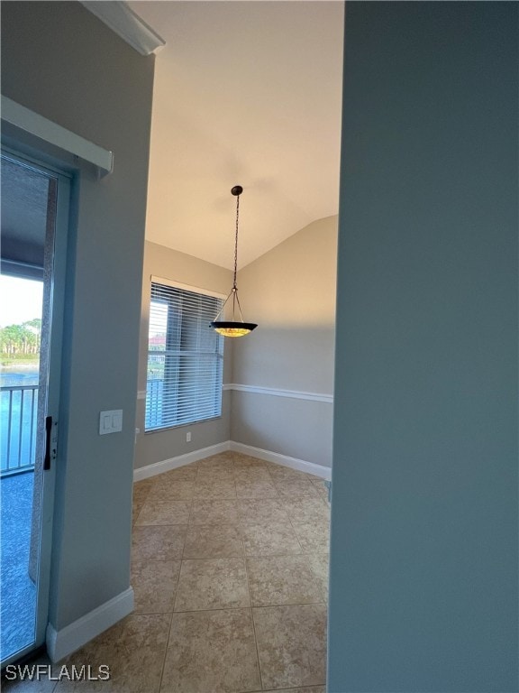 tiled spare room featuring vaulted ceiling, plenty of natural light, and baseboards