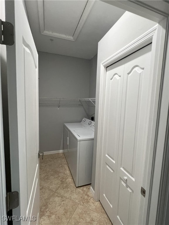 clothes washing area featuring baseboards, light tile patterned flooring, laundry area, and washing machine and clothes dryer