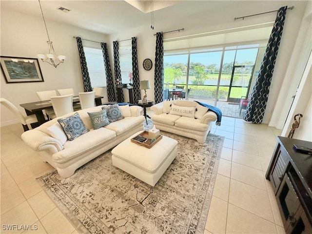 living room with light tile patterned floors, visible vents, and an inviting chandelier