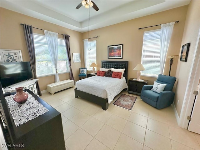 bedroom featuring light tile patterned floors, a tray ceiling, and baseboards