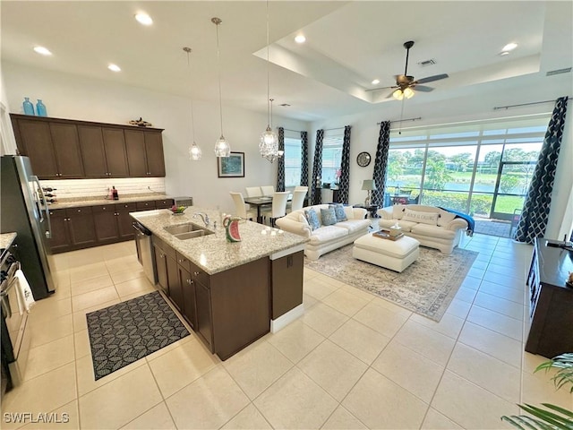 kitchen with visible vents, a sink, a tray ceiling, stainless steel appliances, and dark brown cabinets