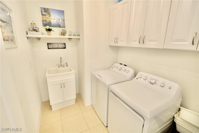 laundry area with baseboards, light tile patterned flooring, cabinet space, a sink, and washer and dryer