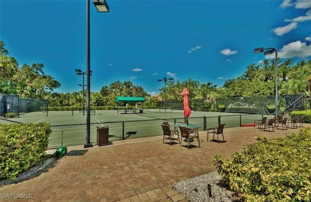 view of community featuring a tennis court and fence