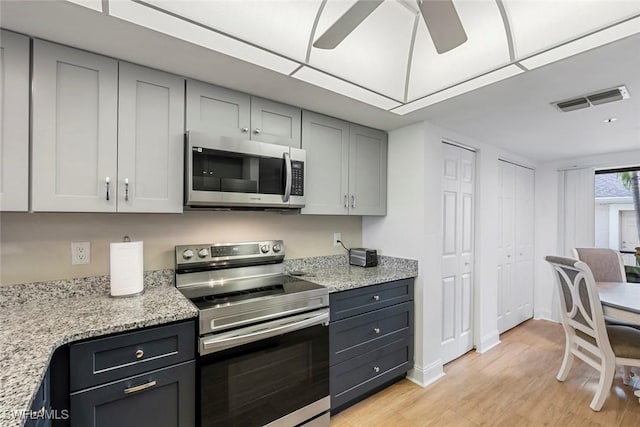 kitchen featuring light stone countertops, visible vents, light wood finished floors, ceiling fan, and stainless steel appliances