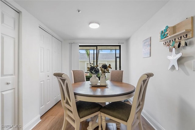 dining space with light wood-type flooring and baseboards