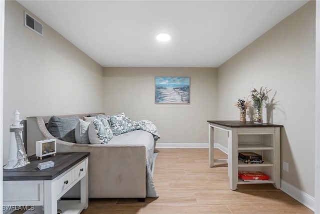 living room featuring light wood-type flooring, visible vents, and baseboards