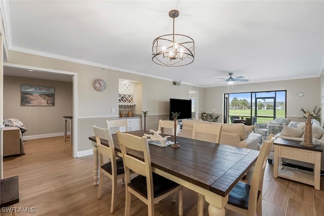 dining area with crown molding, light wood-style floors, baseboards, and visible vents