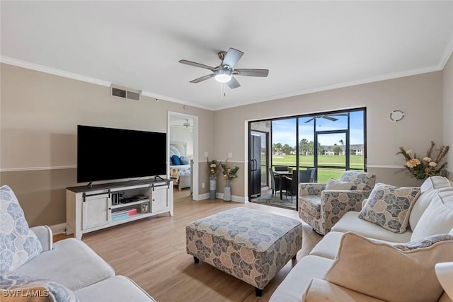 living room featuring visible vents, crown molding, baseboards, light wood-type flooring, and a ceiling fan