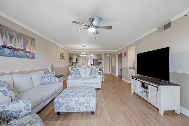 living area featuring baseboards, visible vents, wood tiled floor, crown molding, and ceiling fan with notable chandelier