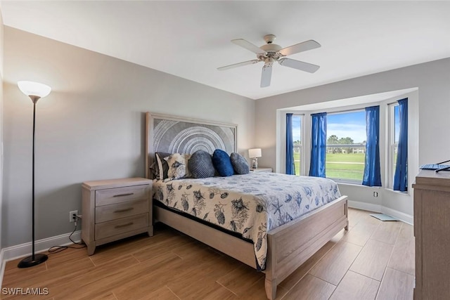 bedroom with baseboards, light wood-style floors, and a ceiling fan