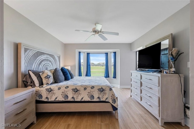 bedroom featuring a ceiling fan, light wood-style floors, and baseboards