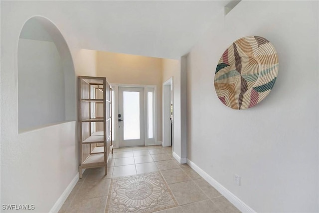 entryway featuring light tile patterned flooring, arched walkways, and baseboards