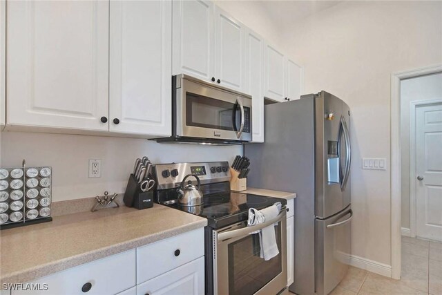 kitchen with light tile patterned flooring, white cabinetry, stainless steel appliances, and light countertops