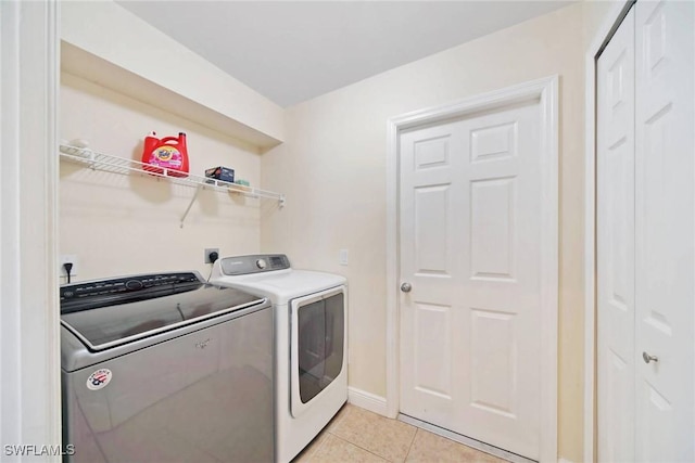 laundry area featuring washing machine and clothes dryer, laundry area, baseboards, and light tile patterned floors