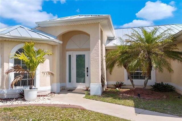 doorway to property featuring stucco siding, metal roof, and a standing seam roof