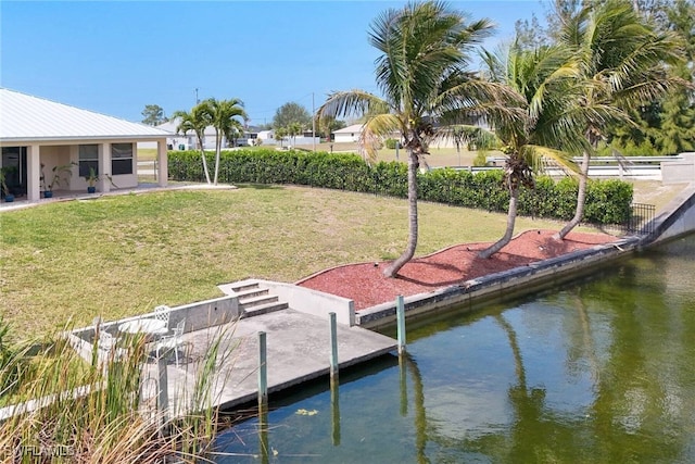 dock area featuring fence, a lawn, and a water view