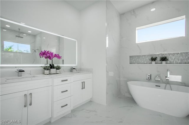 bathroom featuring double vanity, marble finish floor, a freestanding tub, and a sink