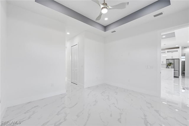 empty room featuring a raised ceiling, visible vents, marble finish floor, and baseboards