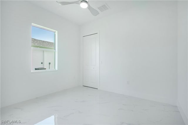 spare room with marble finish floor, baseboards, visible vents, and a ceiling fan