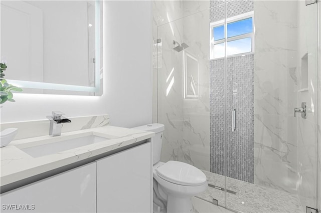 bathroom featuring vanity, a marble finish shower, and toilet