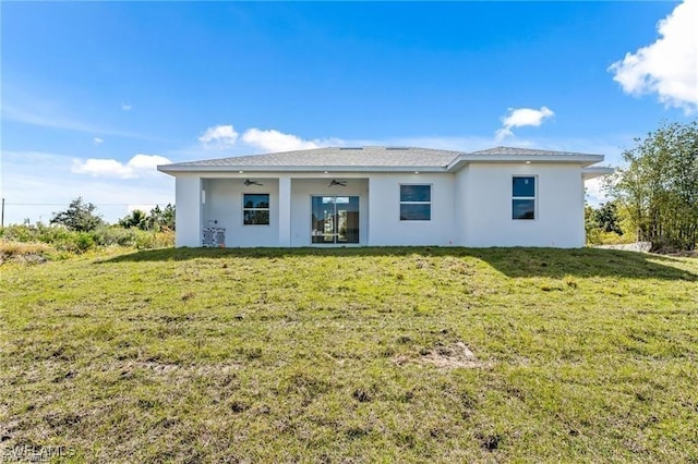 back of property featuring a ceiling fan and a yard