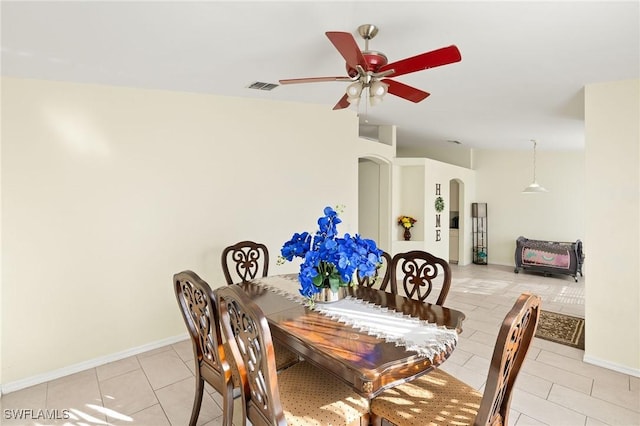 dining room with visible vents, arched walkways, baseboards, ceiling fan, and light tile patterned flooring