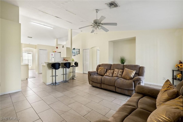 living room with light tile patterned floors, vaulted ceiling, visible vents, and arched walkways