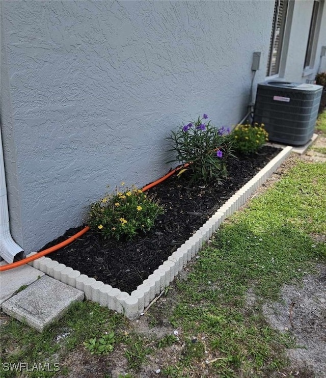 exterior details with stucco siding and central AC