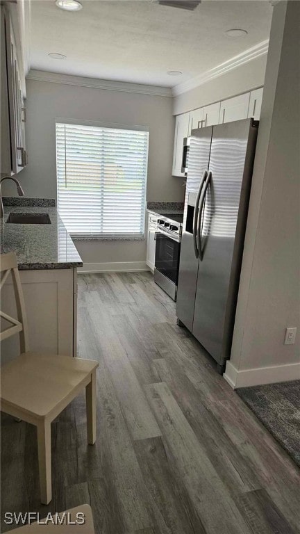 kitchen featuring crown molding, wood finished floors, white cabinets, stainless steel appliances, and a sink