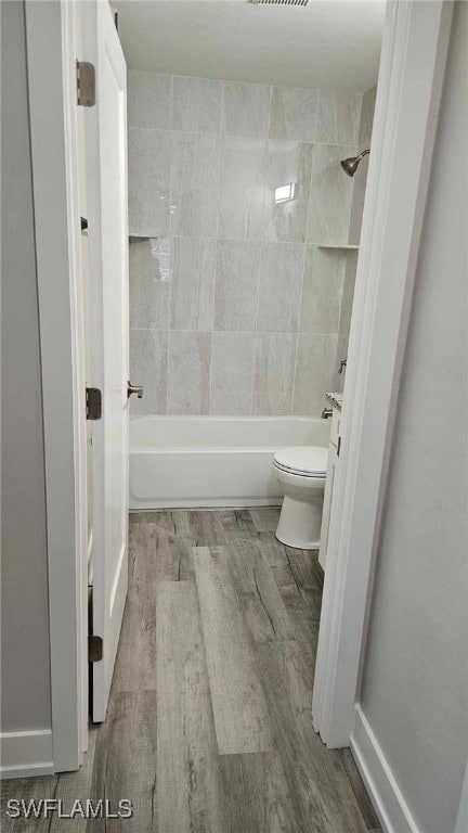 full bath with toilet,  shower combination, and wood finished floors